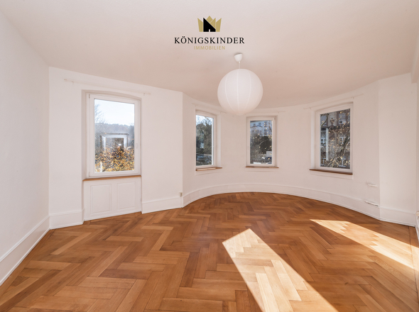 Wohnzimmer mit geschwungener Wand und charmantem Fischgrätparkett...