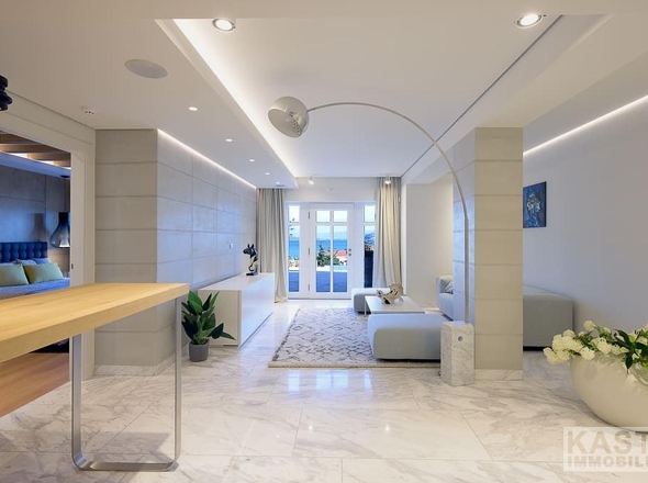 The current title "Badezimmer" is not appropriate for this image. This appears to be a luxury hotel or residential lobby/entrance area, not a bathroom. 

Based on the visible content (spacious entrance hall with marble flooring, reception desk, seating area, and access to other rooms), the appropriate title would be:

**Eingangsbereich**